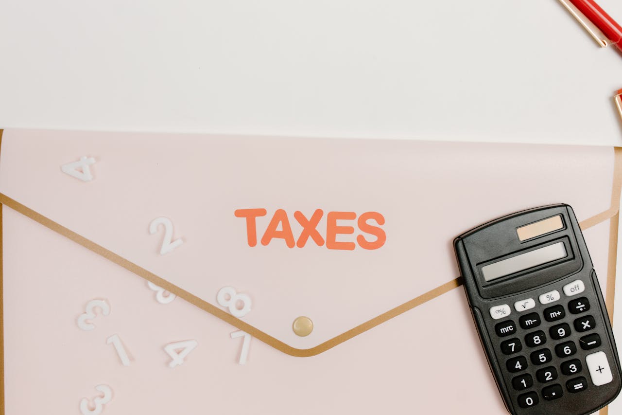 Flat lay of a calculator and folder labeled 'Taxes' for finance and accounting.